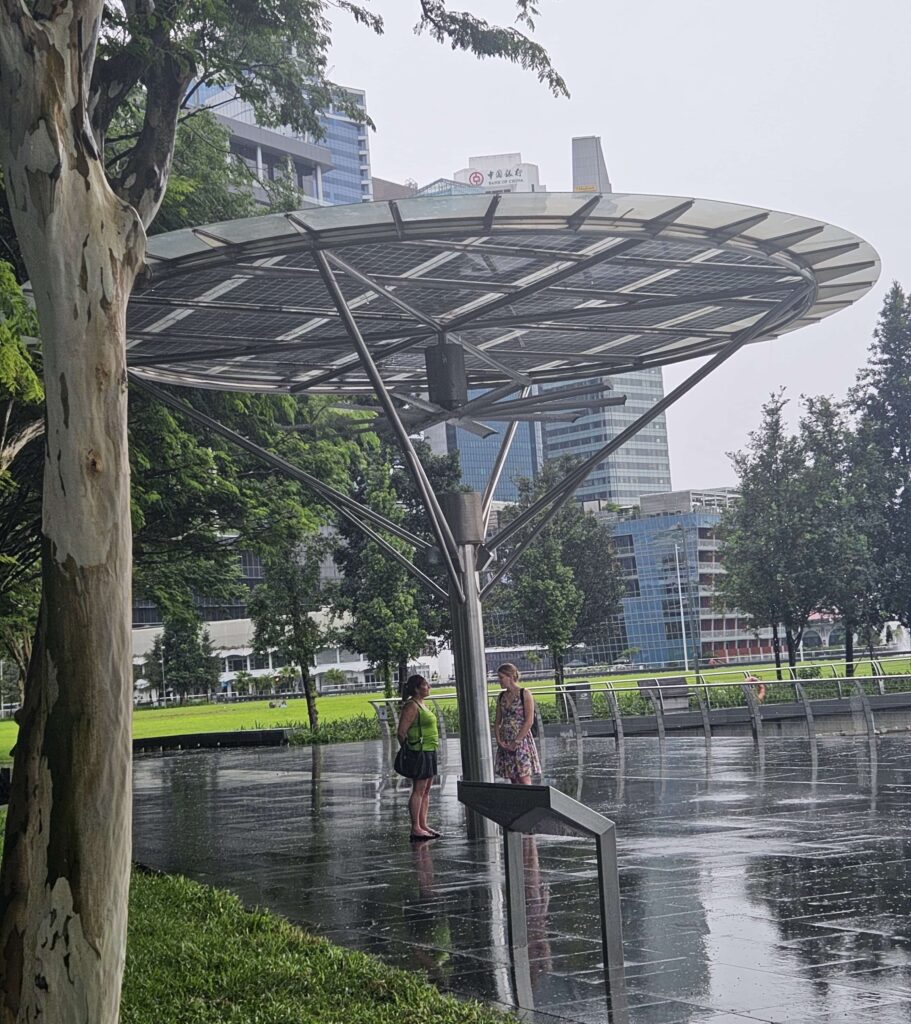 People using the covered solar energy powered fans as a shelter for the rain in Singapore