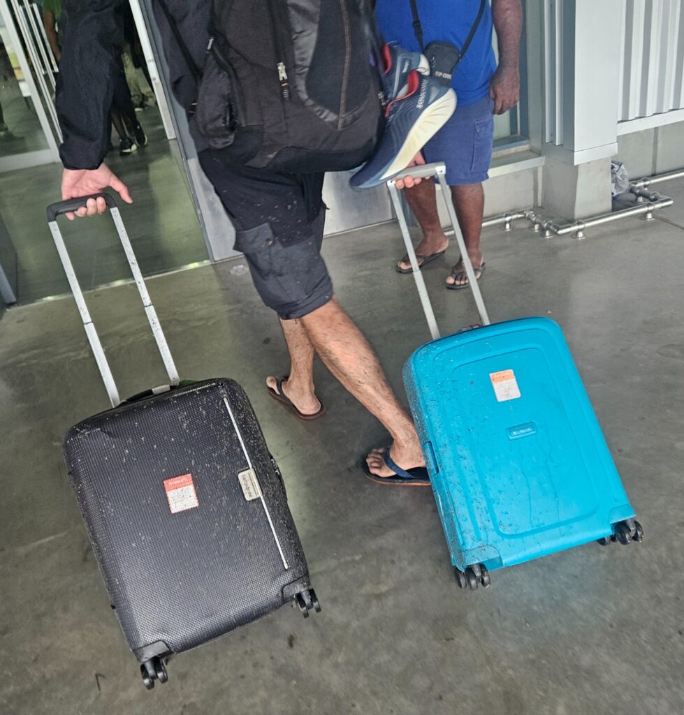 Carrying two suitcases after having walked to the airport in Honiara